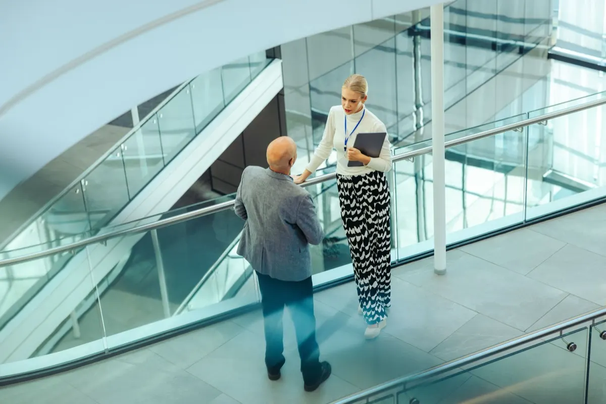 Two colleagues talking on an office mezzanine walkway